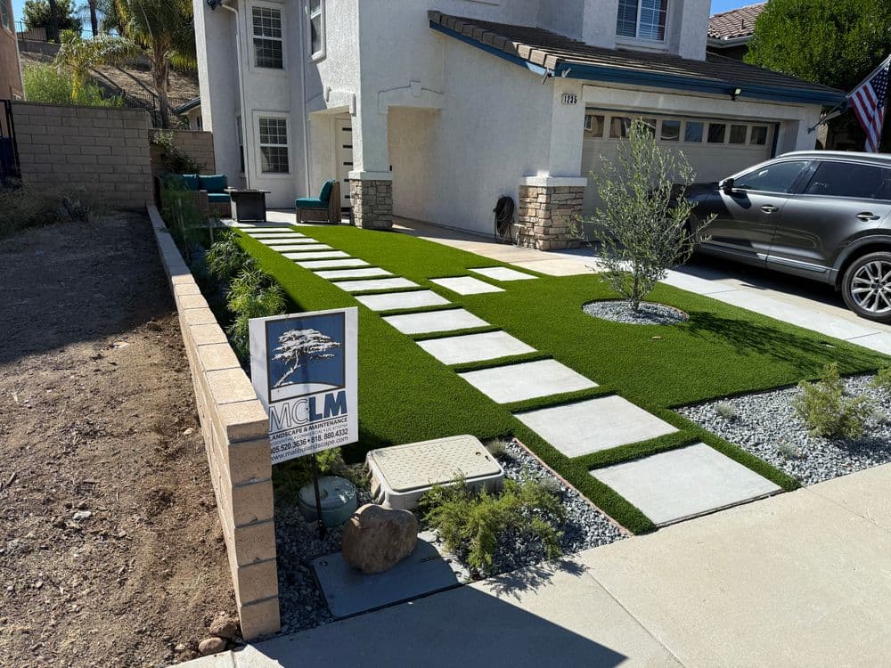 Modern front yard with artificial turf, stone pathway, and landscaping features.